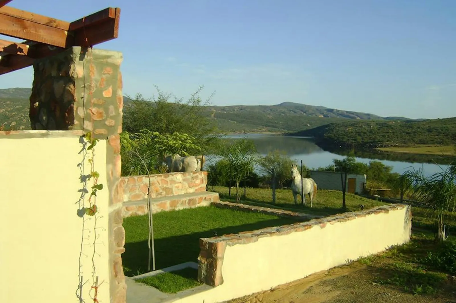 Walled lawn with a white horse above the water at 5-Sleeper 2-bedroom Cottage 1, Rondegat Guest Farm | Rondegat Guest Farm - 5-Sleeper 2-bedroom Cottage 1 - Western Cape - Clanwilliam - Clanwilliam Dam